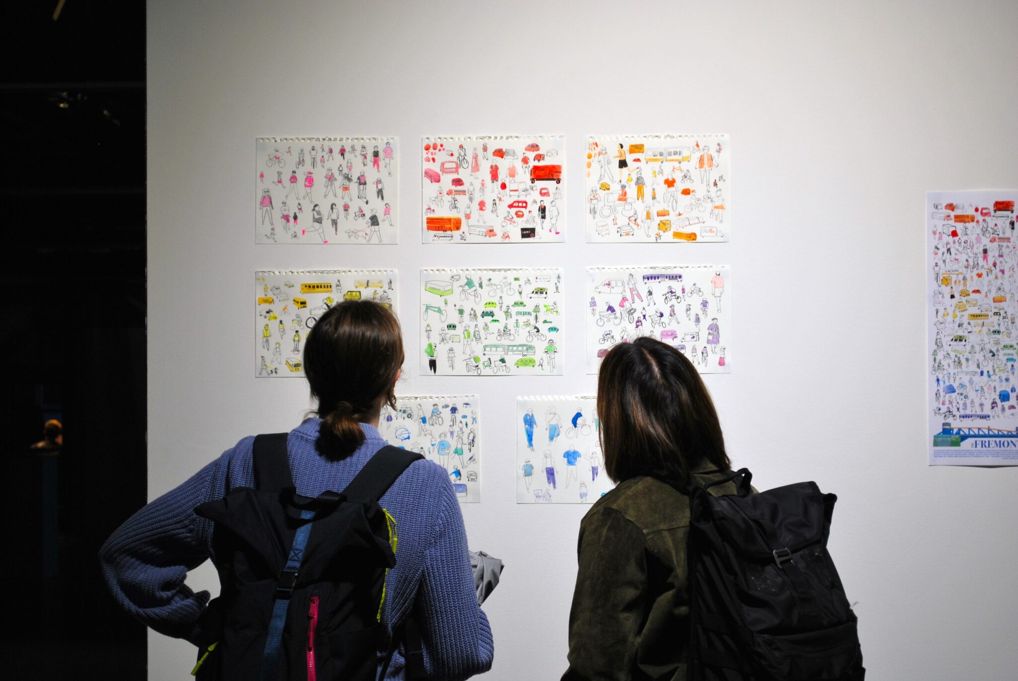 two people looking at illustrations on gallery wall