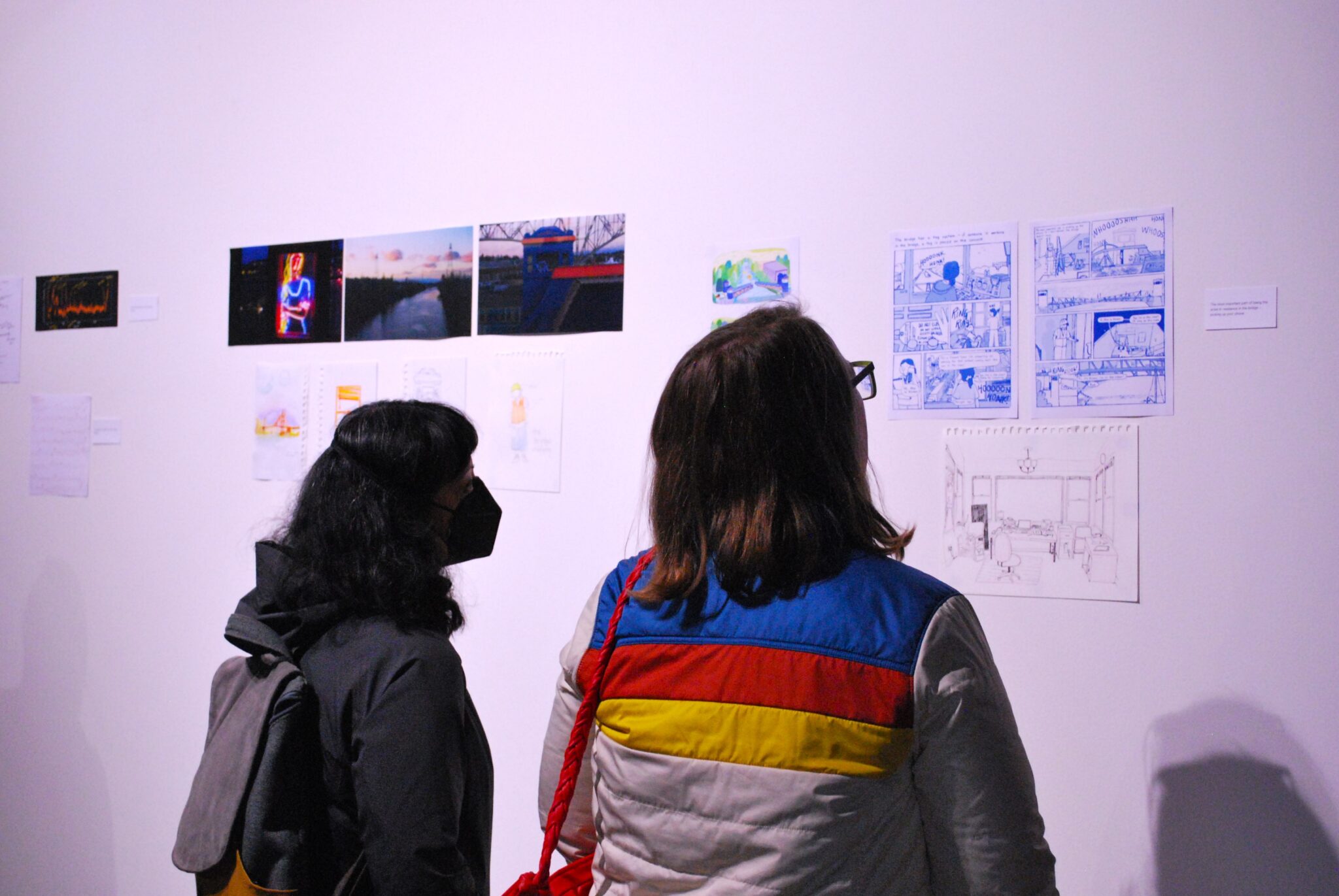 back of two people looking at artwork on gallery wall