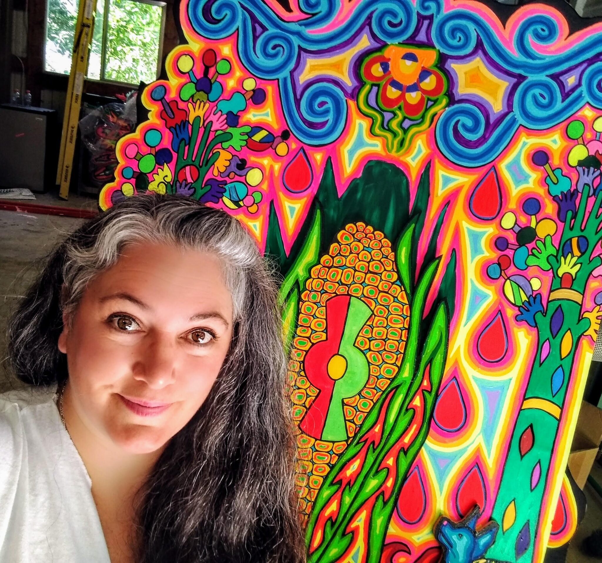 selfie of woman with long hair standing next to colorful painting