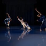 Three Black dancers on stage with black background.