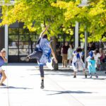 Four Black dancers performing outside in Seattle Center with an audience in the background