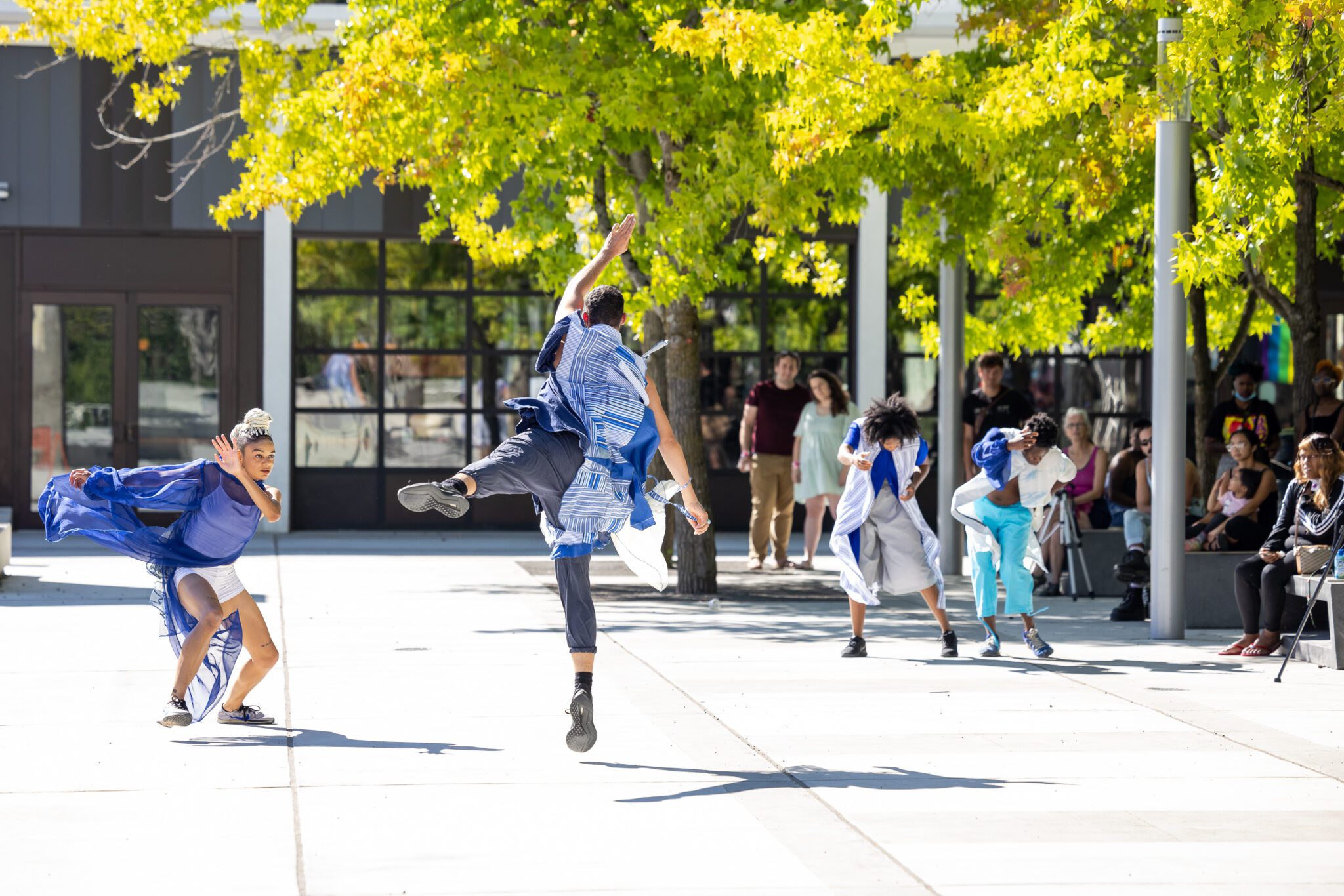 Four Black dancers performing outside in Seattle Center with an audience in the background