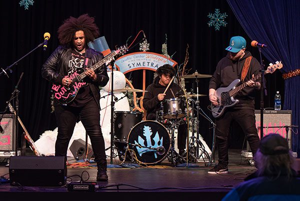 Three men of color in a band perform onstage.