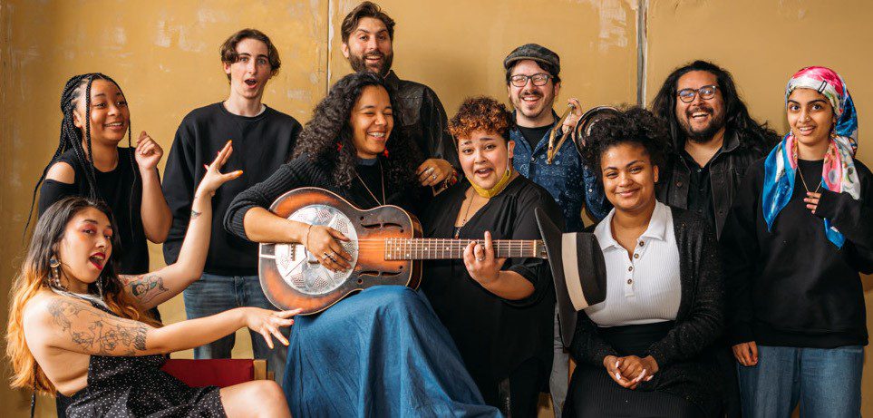 Group of teenager with one holding a guitar.