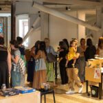 A group of people crowd in the Living Room space at ARTS at King Street Station.