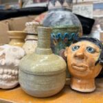 Ceramic pieces in a classroom, including a face, skull, and vase