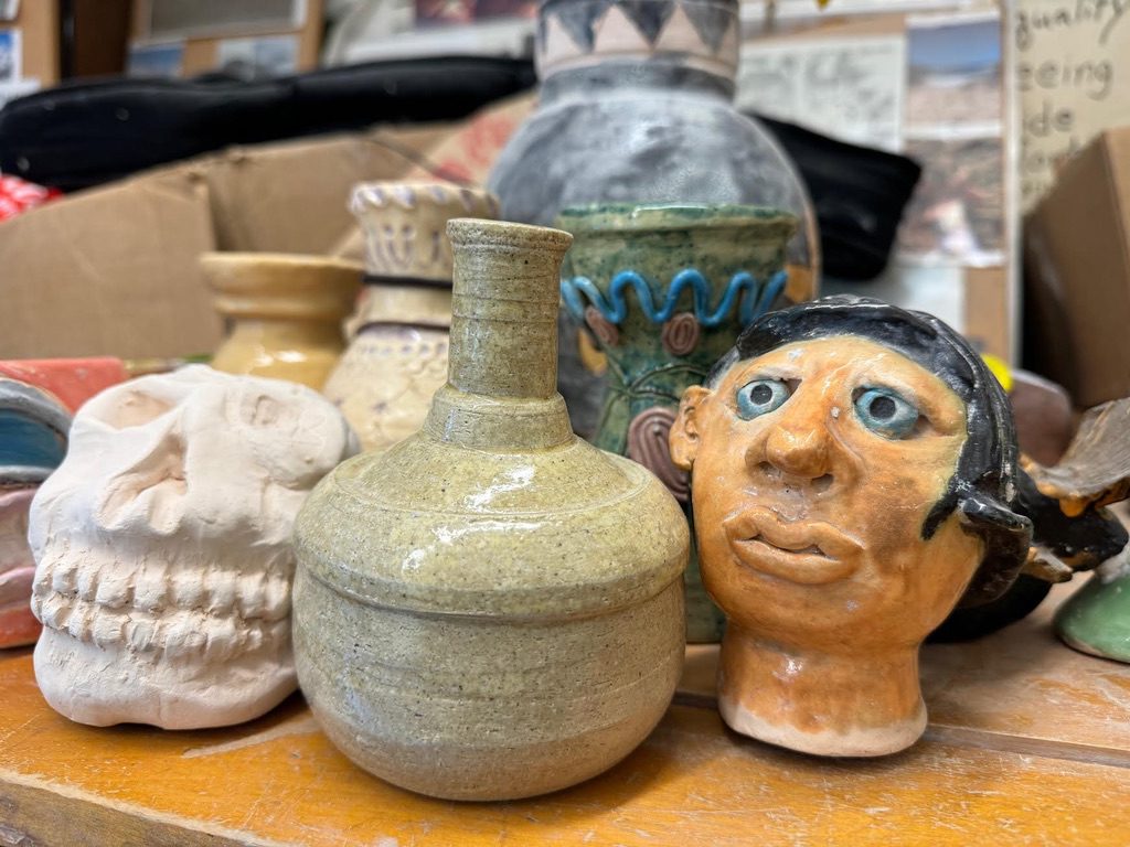 Ceramic pieces in a classroom, including a face, skull, and vase