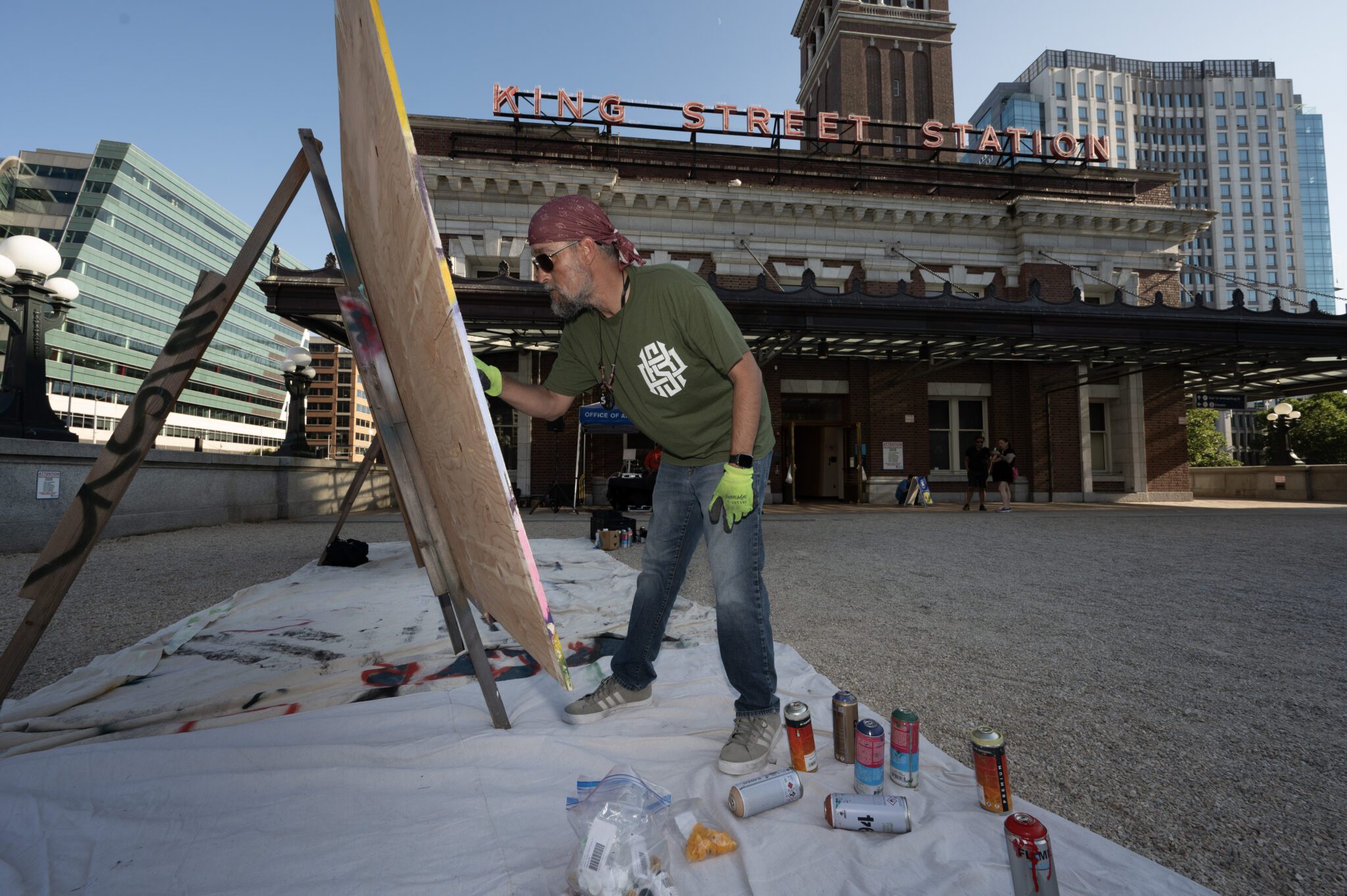 Sire One painting graffiti on canvas in front of King Street Station