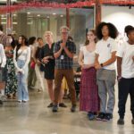 audience stands to listen to speeches at gallery opening reception