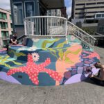 Two women paint colorful, underwater themed mural on large, rounded steps