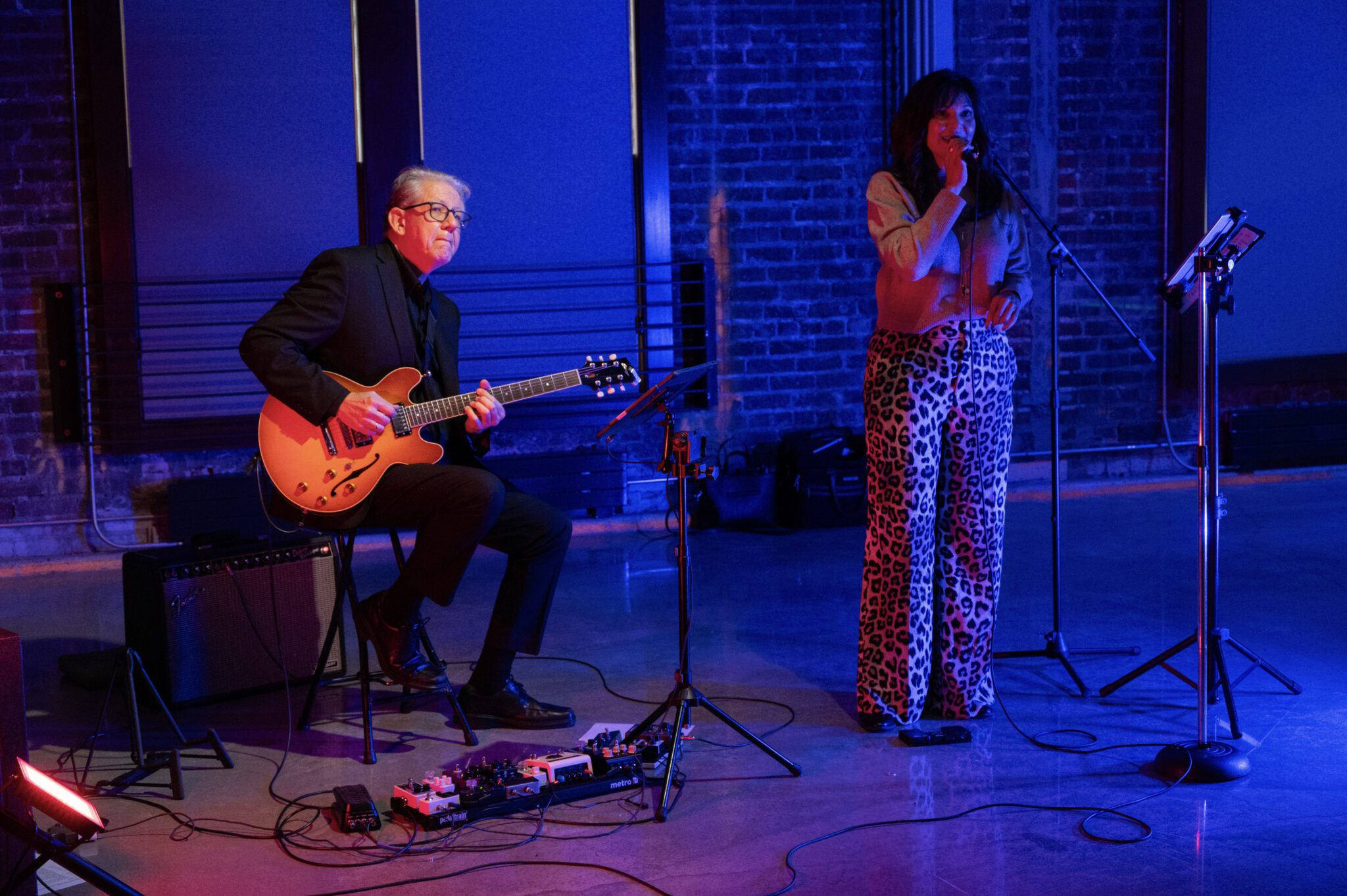 A singer and a guitarist play music under blue light