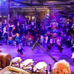 Dancers performing in Indigenous Mexican outfits with a large audience behind them