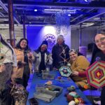 A group of people showing off their handmade yarn ojos de dios.