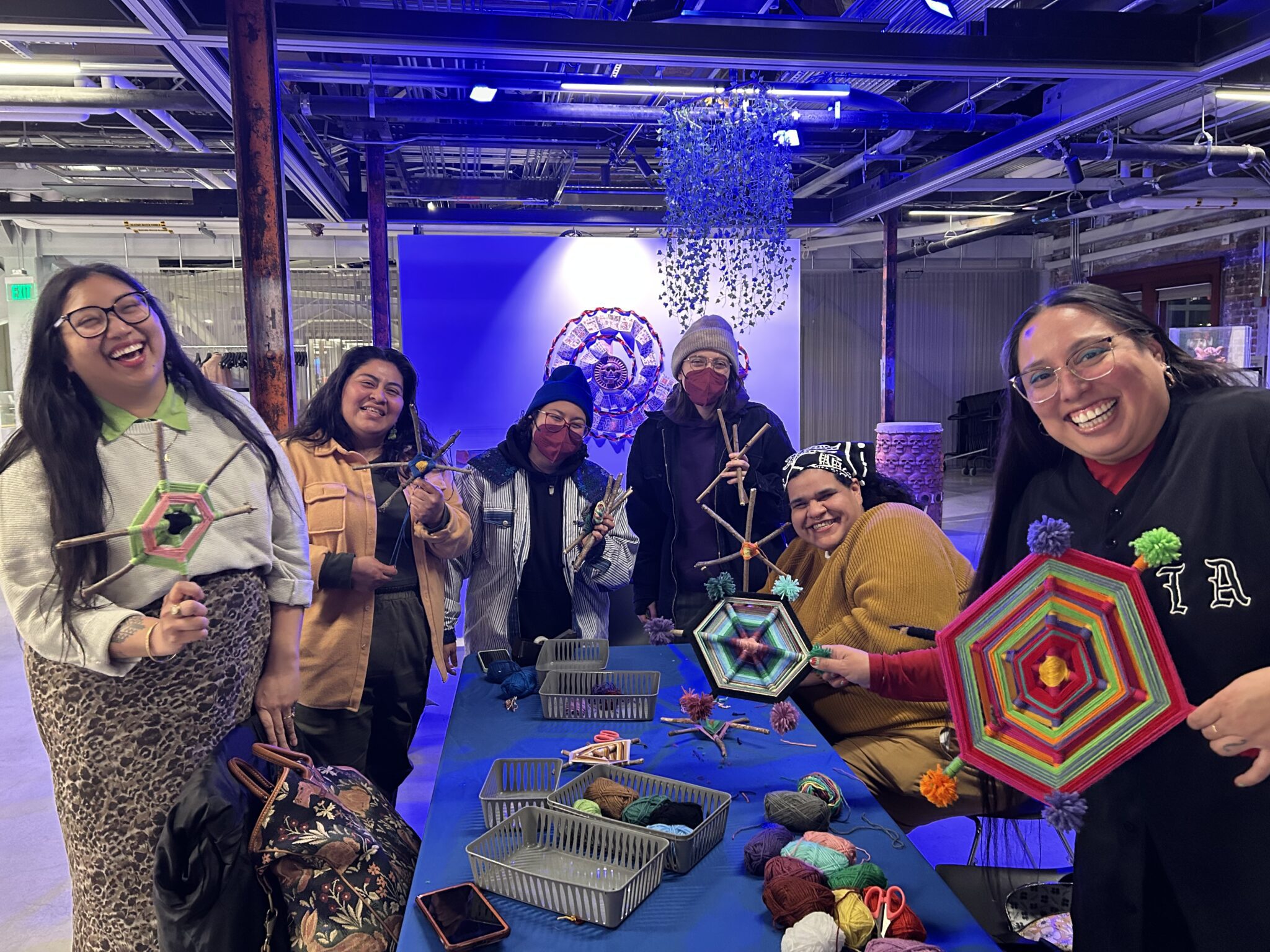 A group of people showing off their handmade yarn ojos de dios.