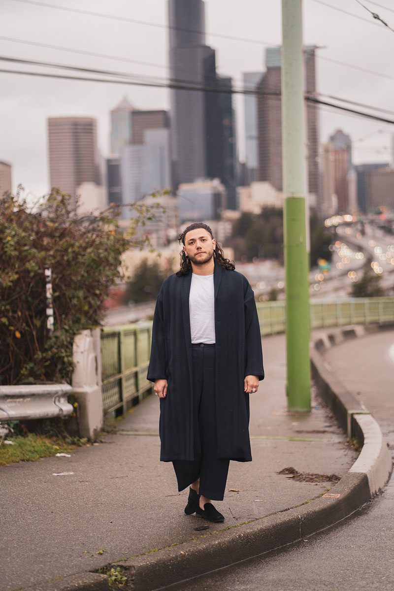 Dujie has long hair and wears long, flowy garments. They're standing on the Jose Rizal Bridge on Beacon Hill.