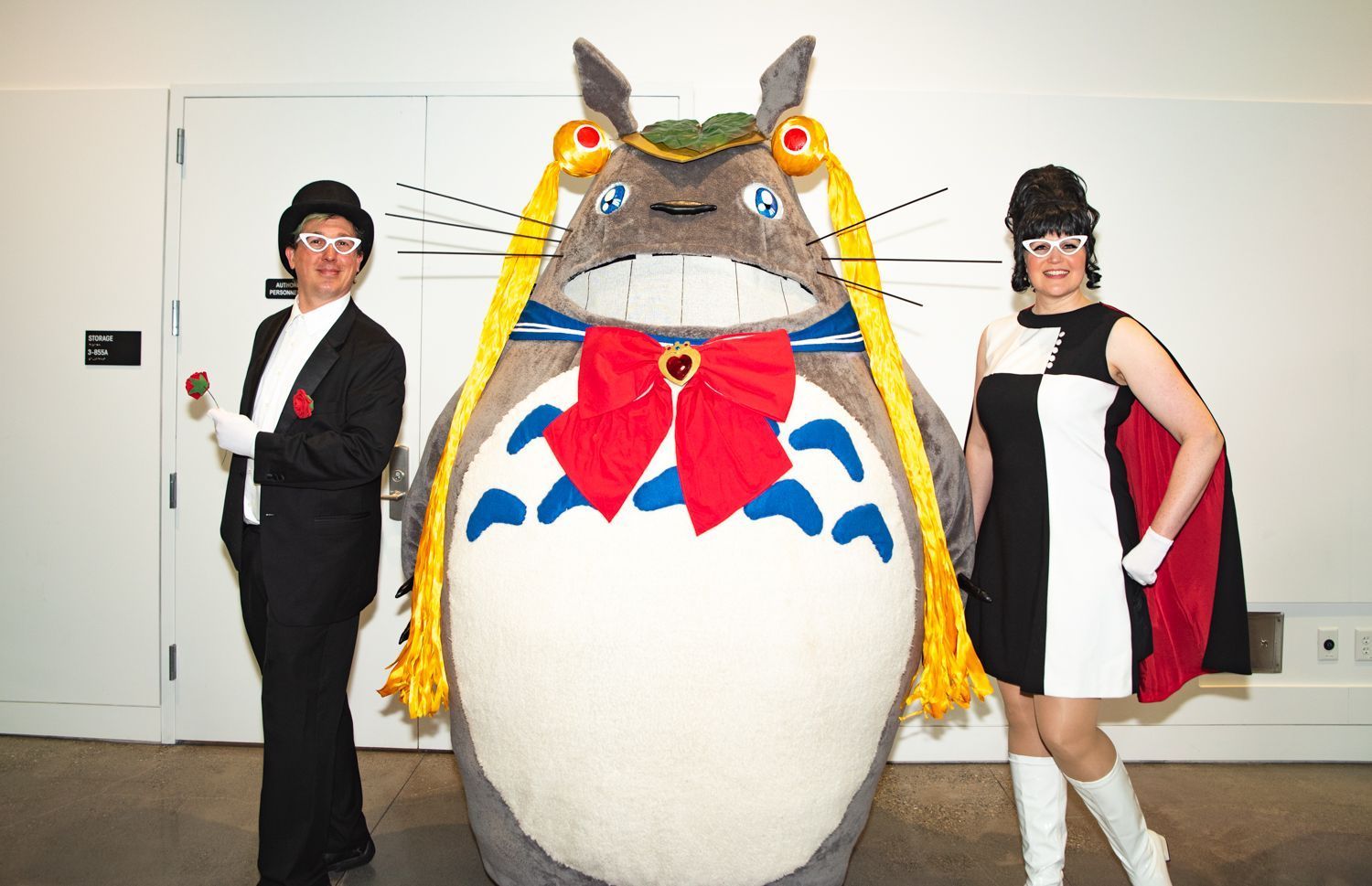 Three cosplayers: two Tuxedo Masks and one large Totoro with Sailor Moon braids and accessories. It's hilarious.