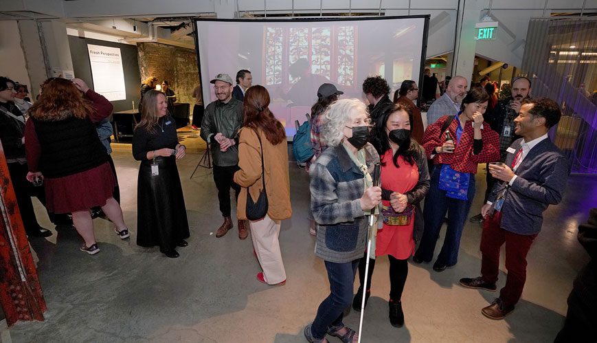 A low vision guest, Barbara, walks arm in arm with Kathy in the gallery