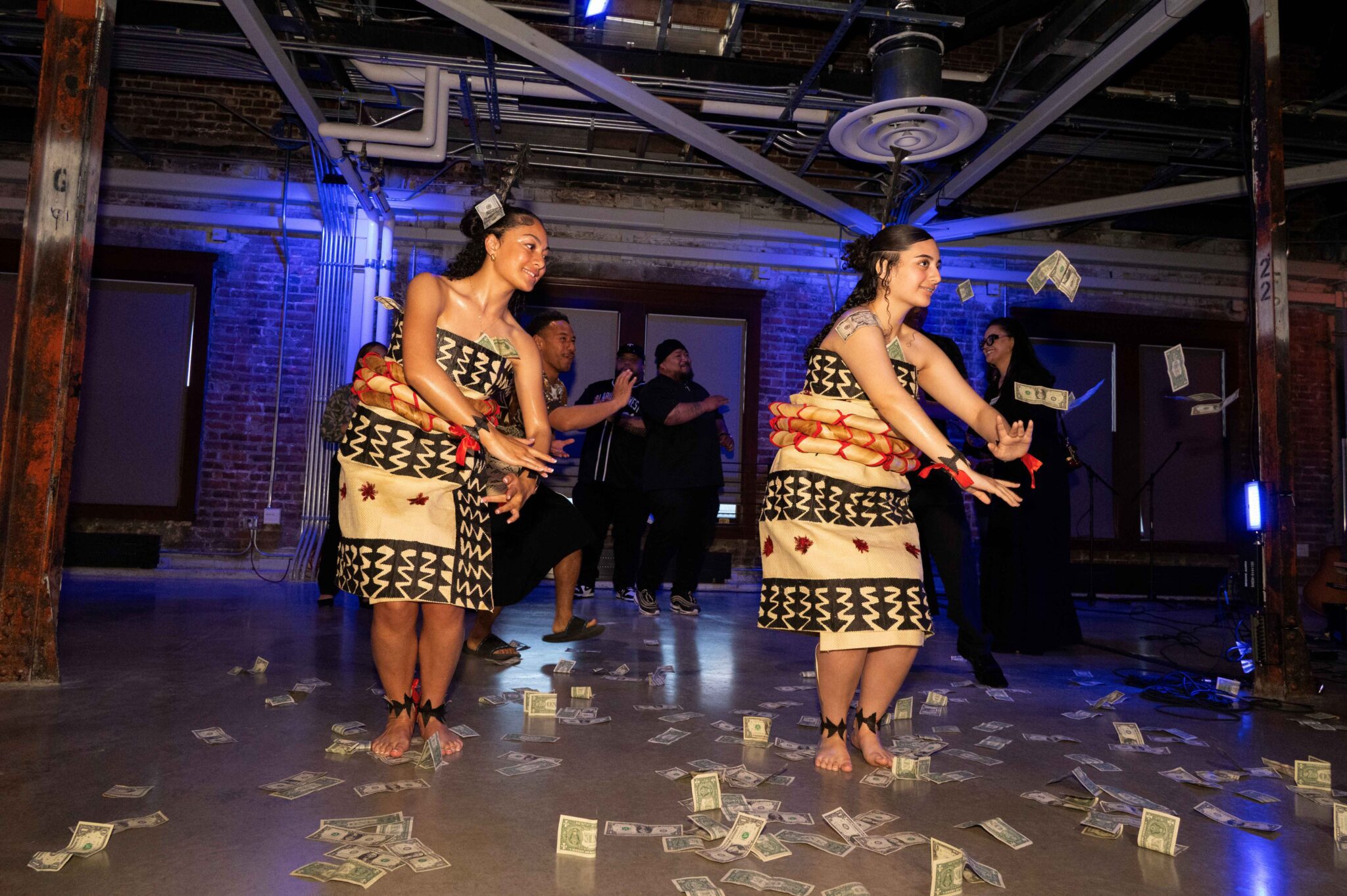 two Tongan dancers with money flying around them