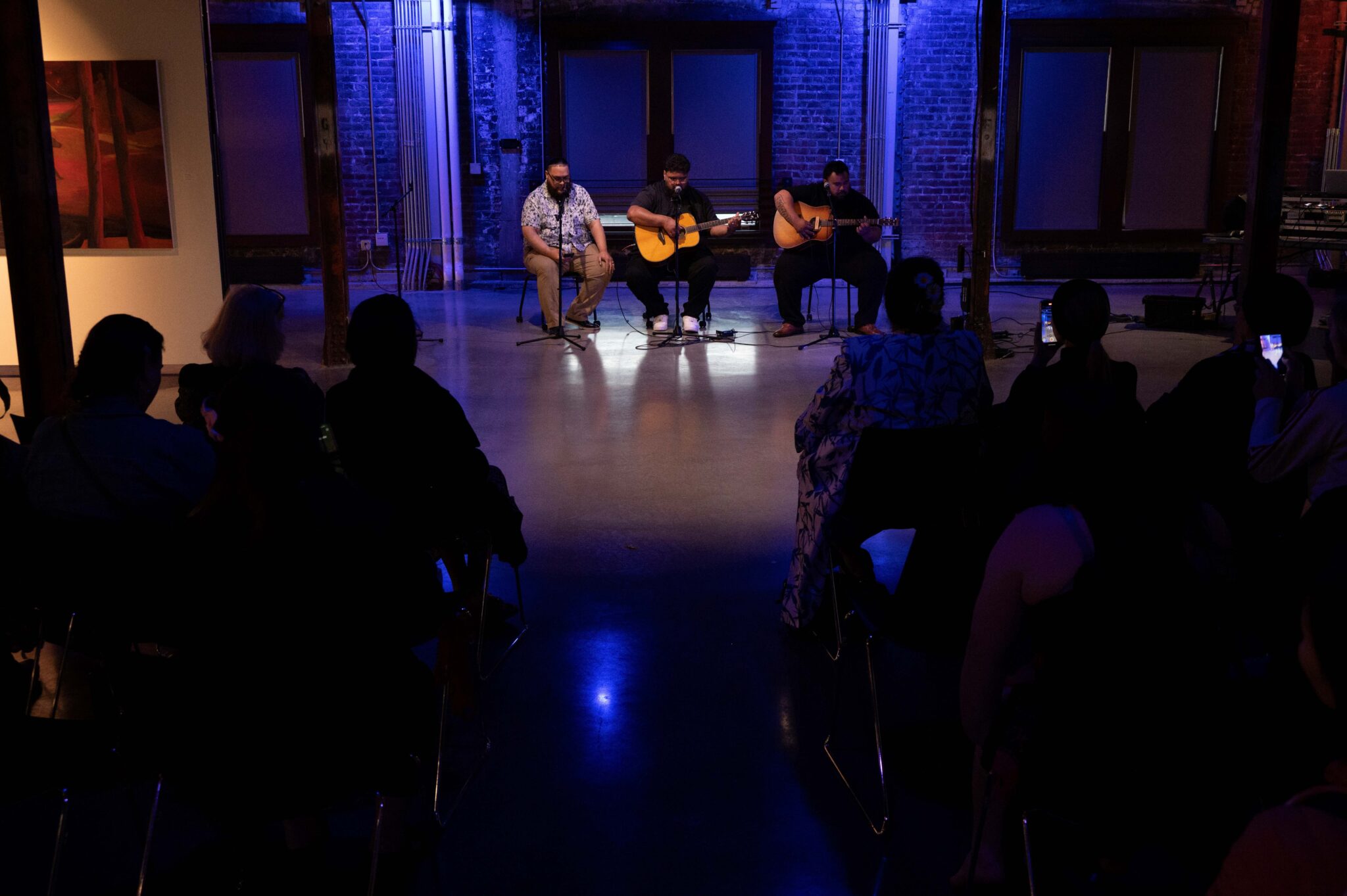 Three men sing and play guitar
