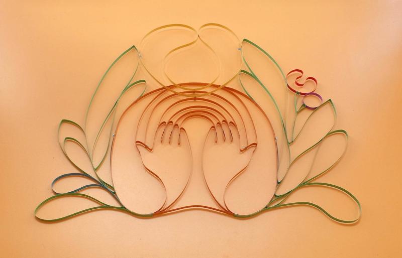 pastel painted steel ribbons in the shape of a woman holding out two hands with flowers blooming around them
