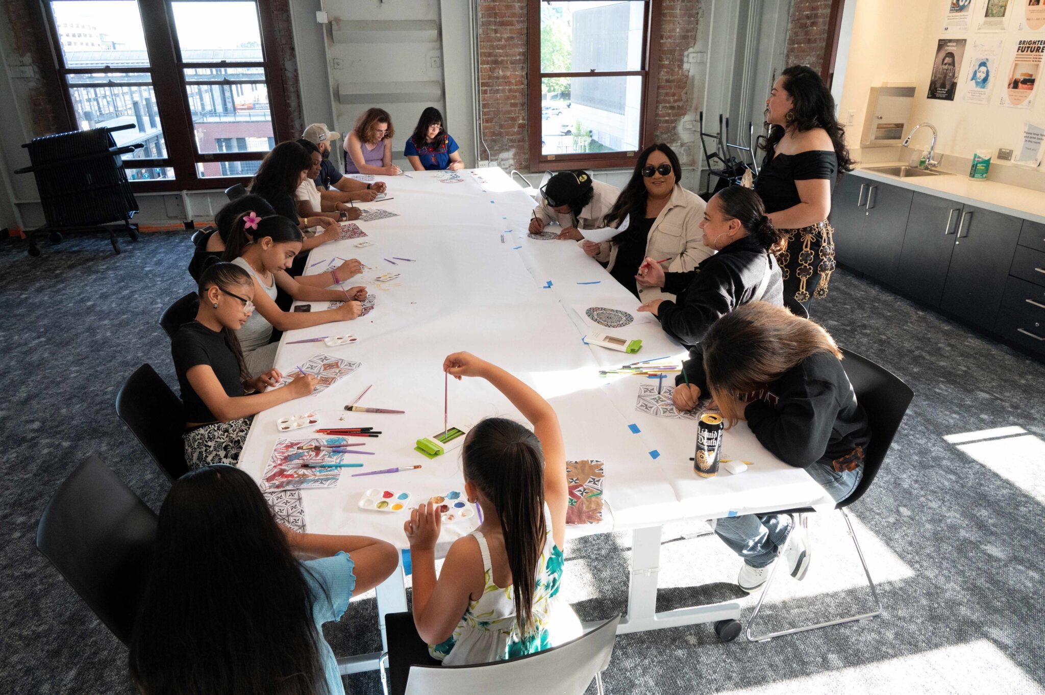 A group of children and adults drawing together at a large table