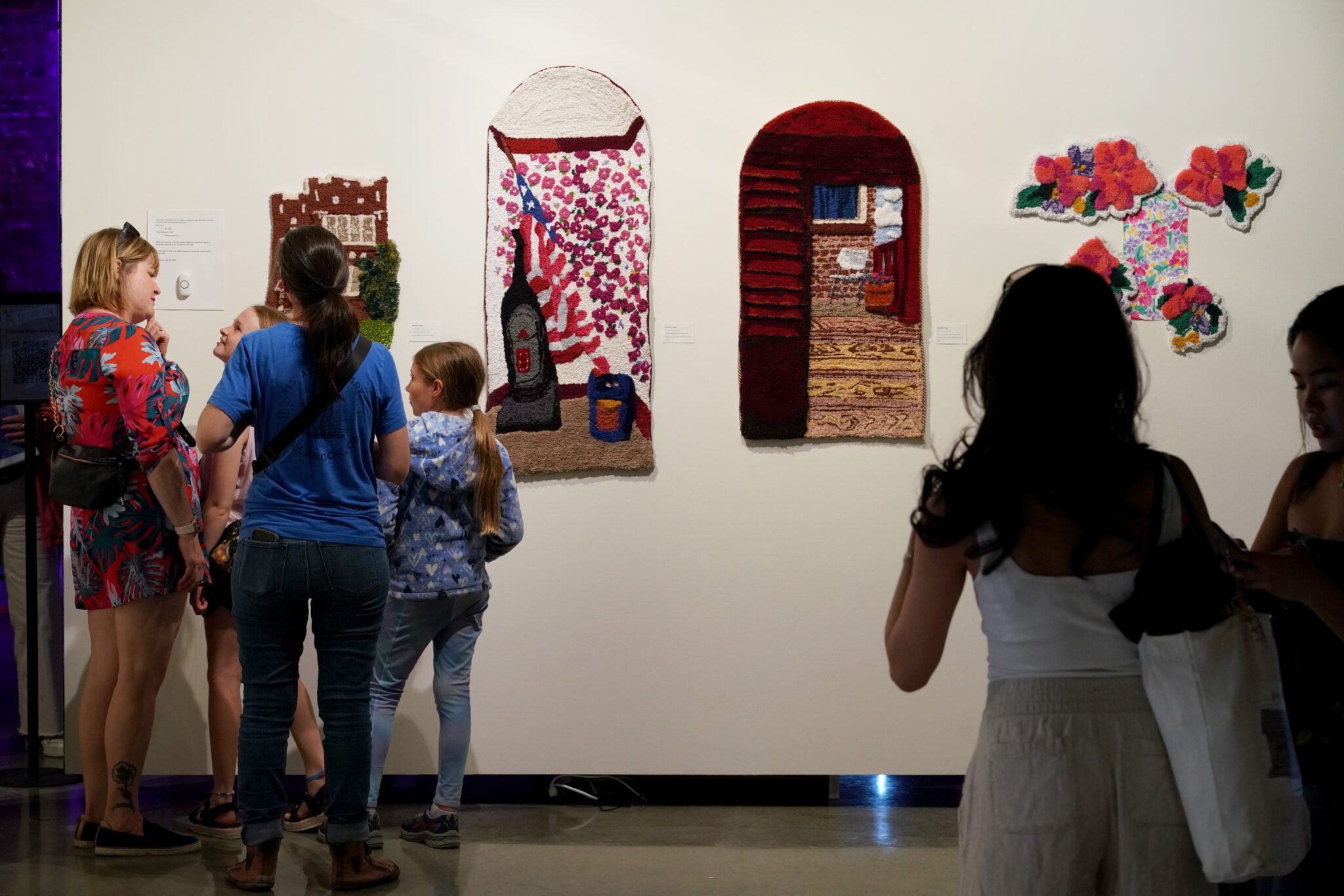 Several groups of people look at art in a gallery.