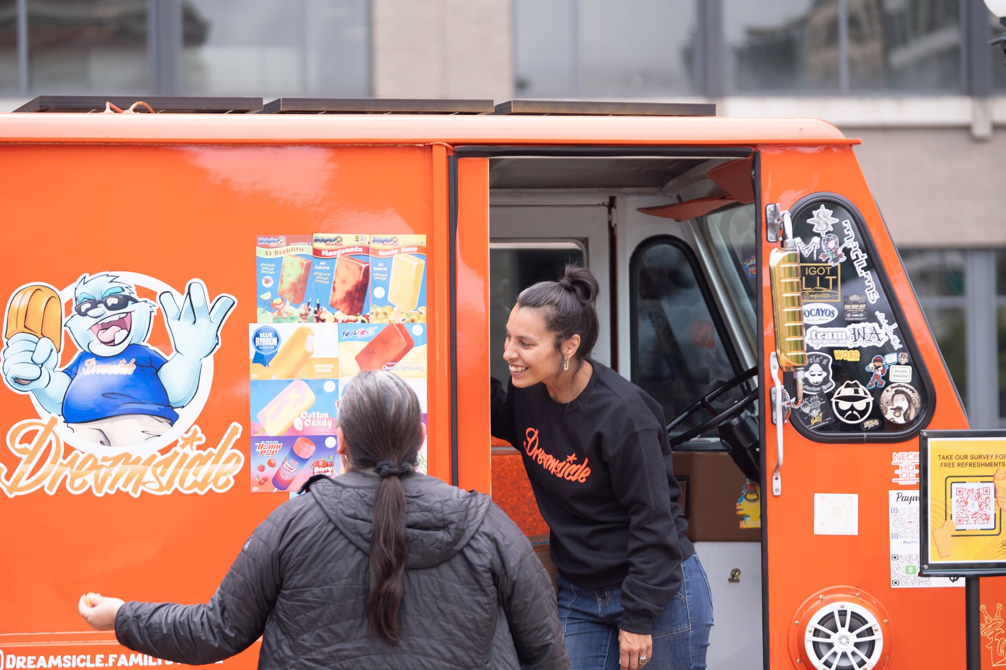 A person smiles in the door of an ice cream truck while talking to someone.