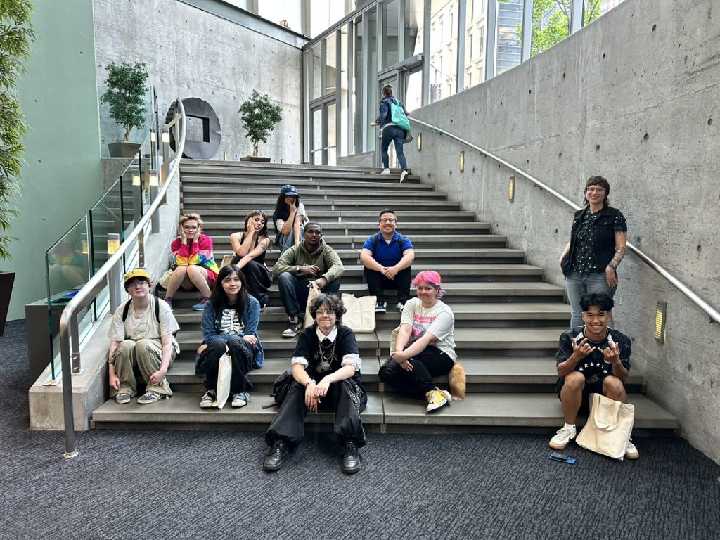 A group of teenagers sitting on the steps at the Seattle Municipal Tower
