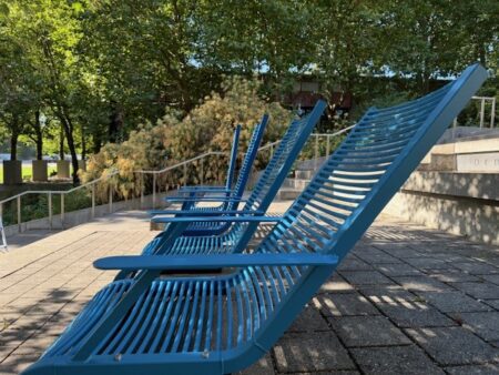 Large bright blue sculptures in the shape of lawn chairs angled to recline.