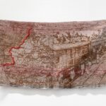 Brown and beige fabric artwork with imagery of a train and a map on India and Pakistan with the partition line outlines in red
