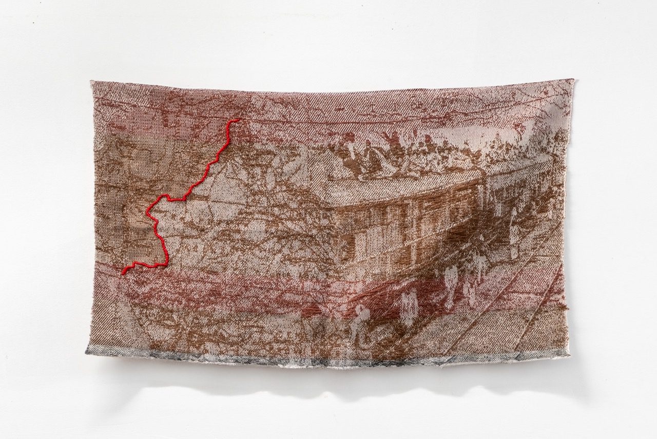 Brown and beige fabric artwork with imagery of a train and a map on India and Pakistan with the partition line outlines in red