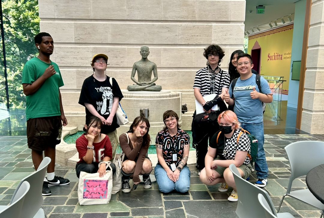 a group of teens and their teacher with a Buddha statue
