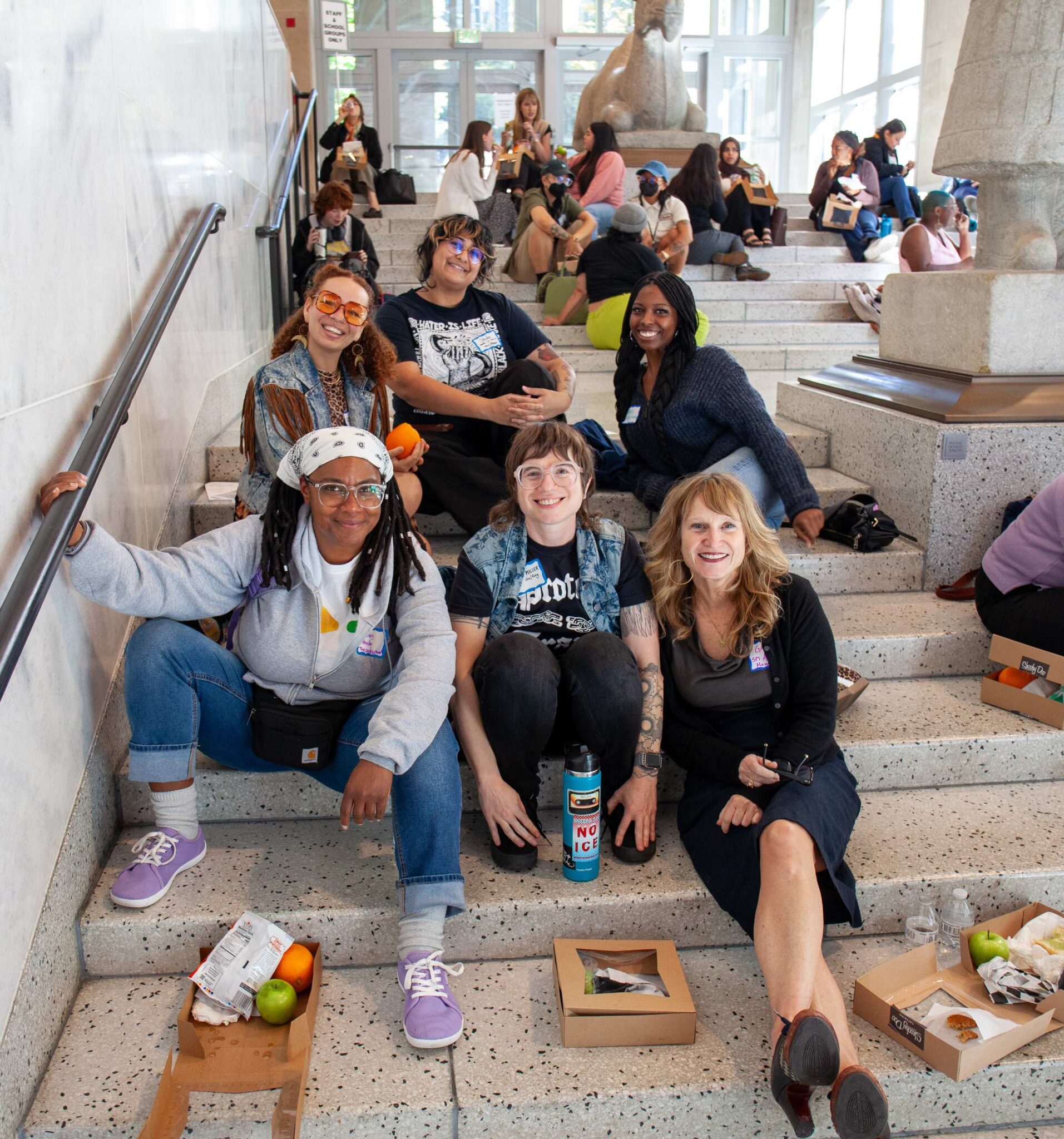 various groups of people sitting on stone steps eating lunch