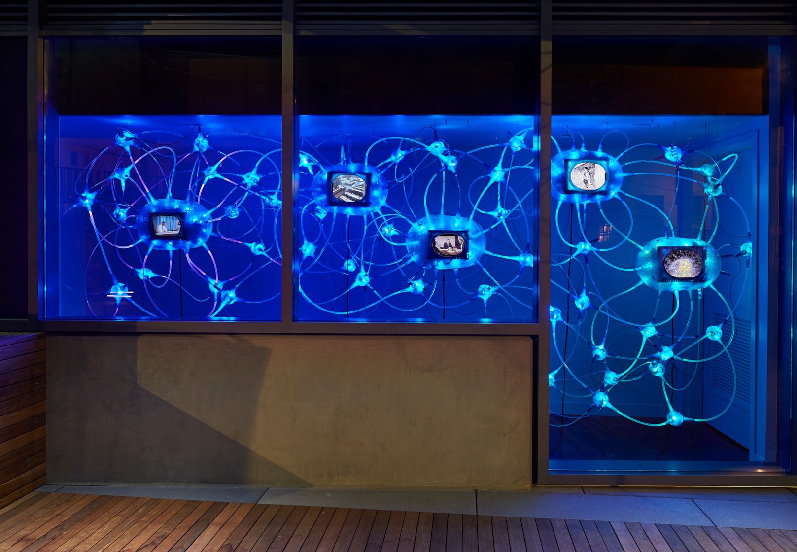 A window installation of small video installations connected by glowing blue tubes