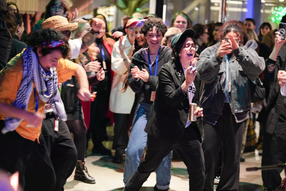 A large group of people dance and laugh together in the gallery