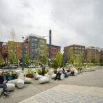 Many cement sculptures sit along a pathway with people sitting on them