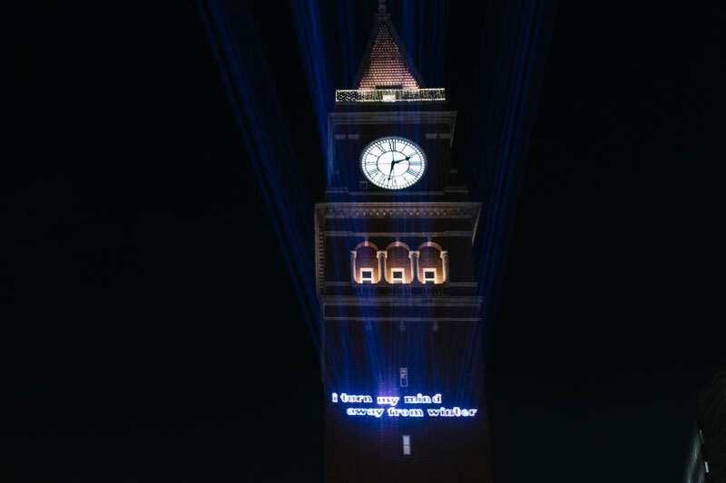 The King Street Station clock tower at night with projected text that reads