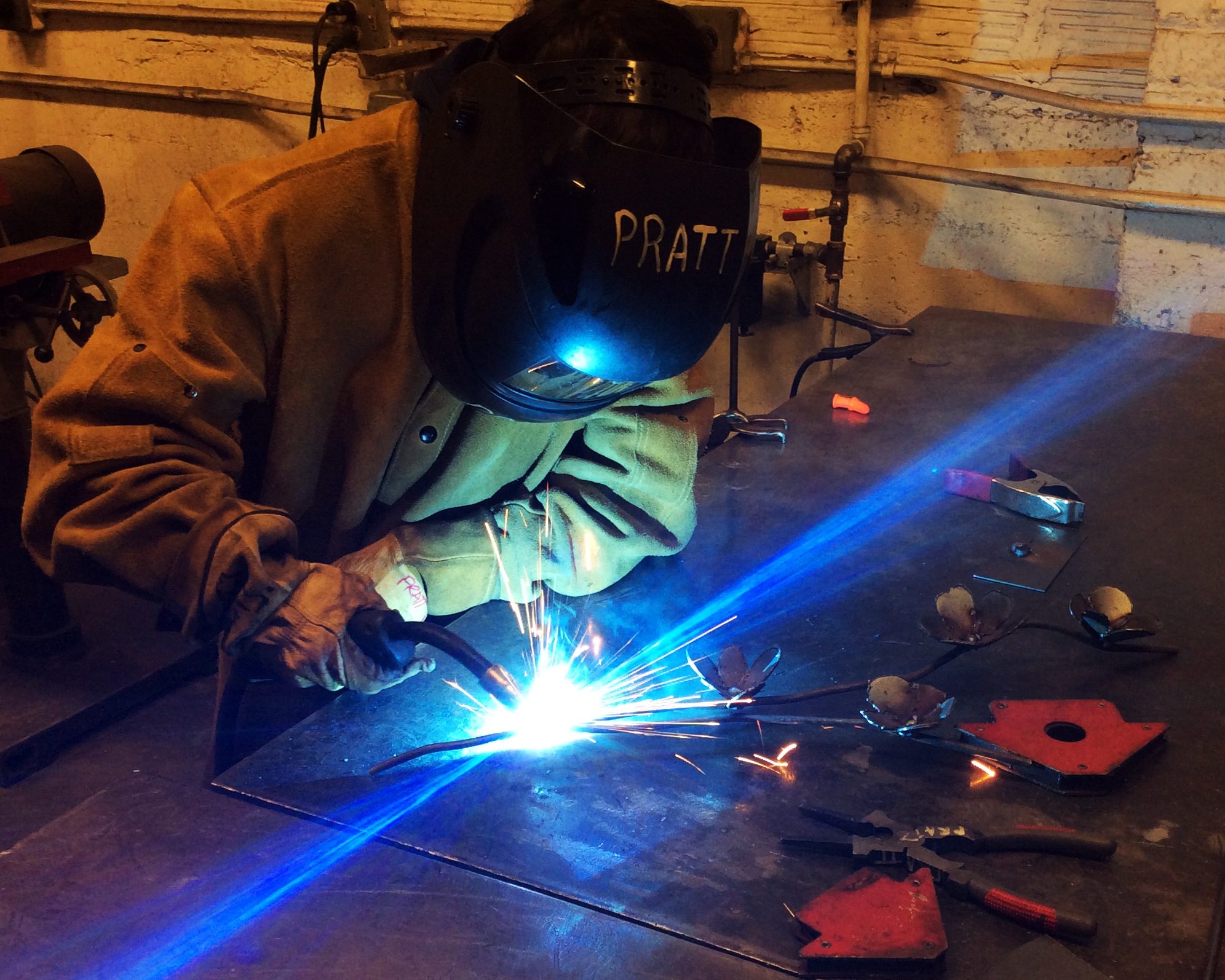A person wearing a helmet welds metal.