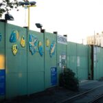 Colorful sea creature illustrations on a green metal fence outside.