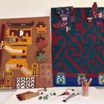 Two collage artworks with Indigenous figures and patterns. Artwork making materials lay in front of the work.