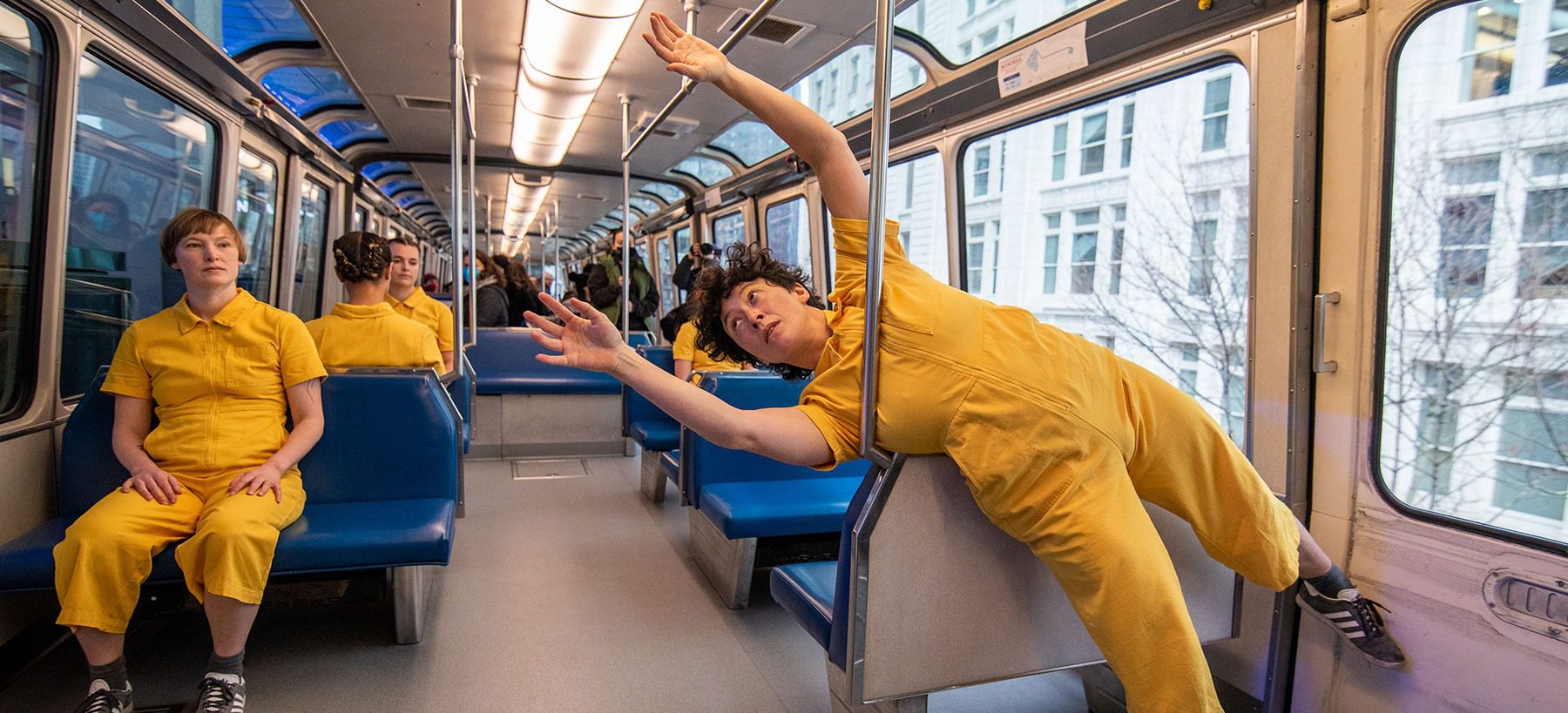 people in yellow jumpsuits dance on the Seattle monorail