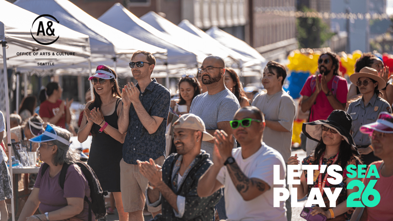 a crowd of people clap at an outdoor street festival.