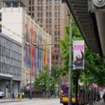 South facing view of the Sound/s installation. Colorful bars are staggered on a beige building.