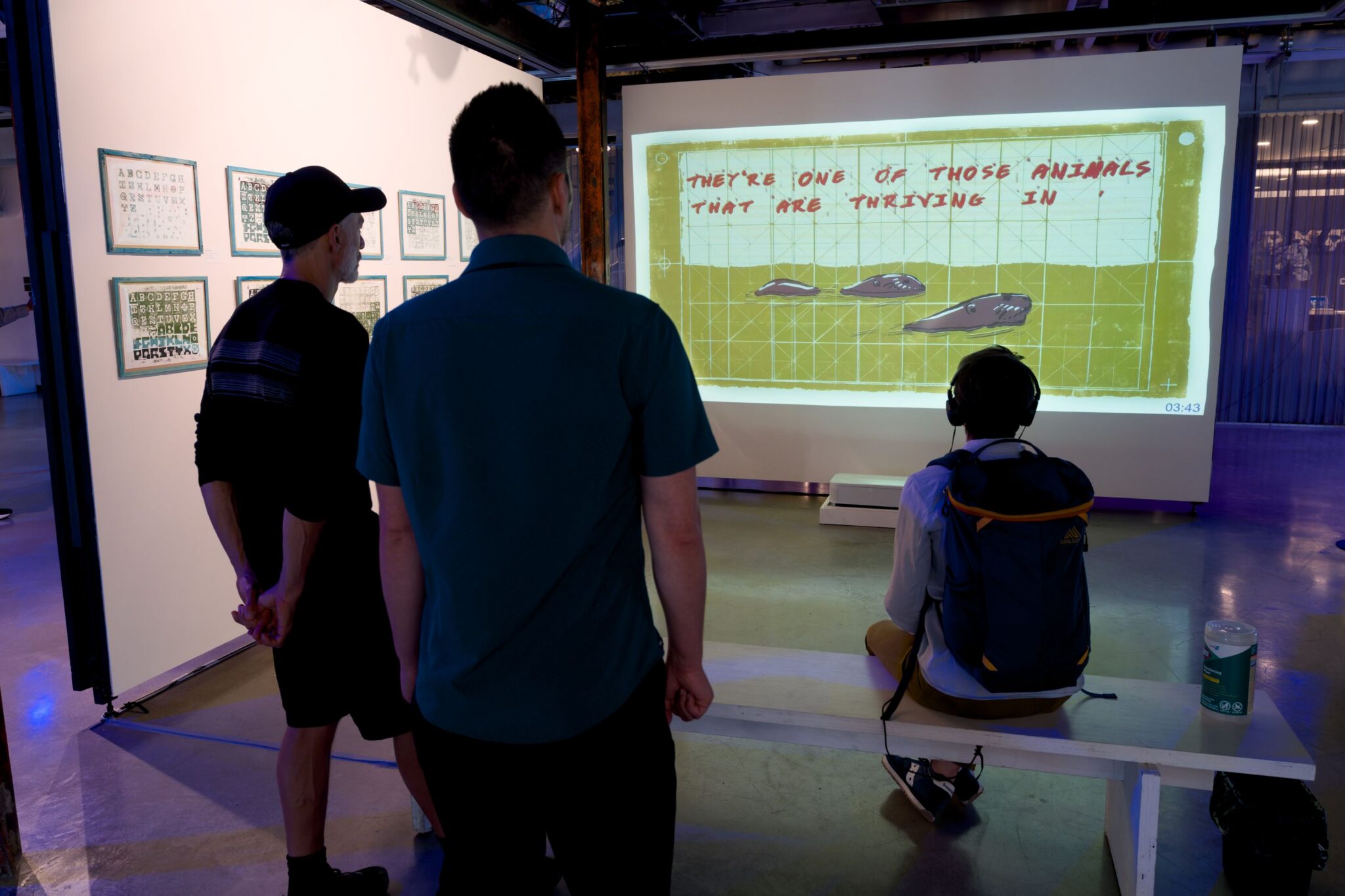 A trio of people watch an animation from the SDOT Bridge Residency from Freyja Whitney.