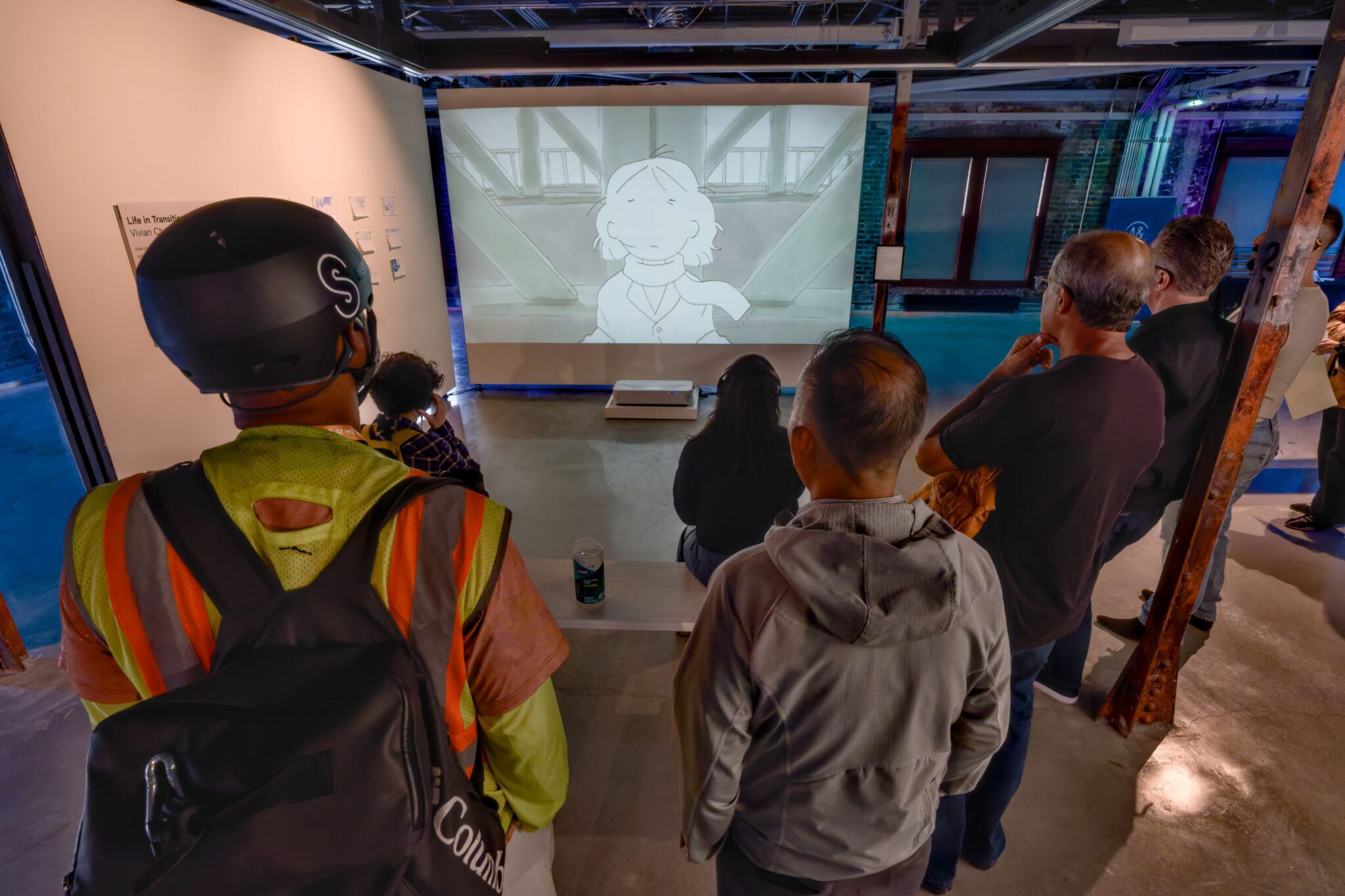 A group of people watch an animated film as part of the exhibit.