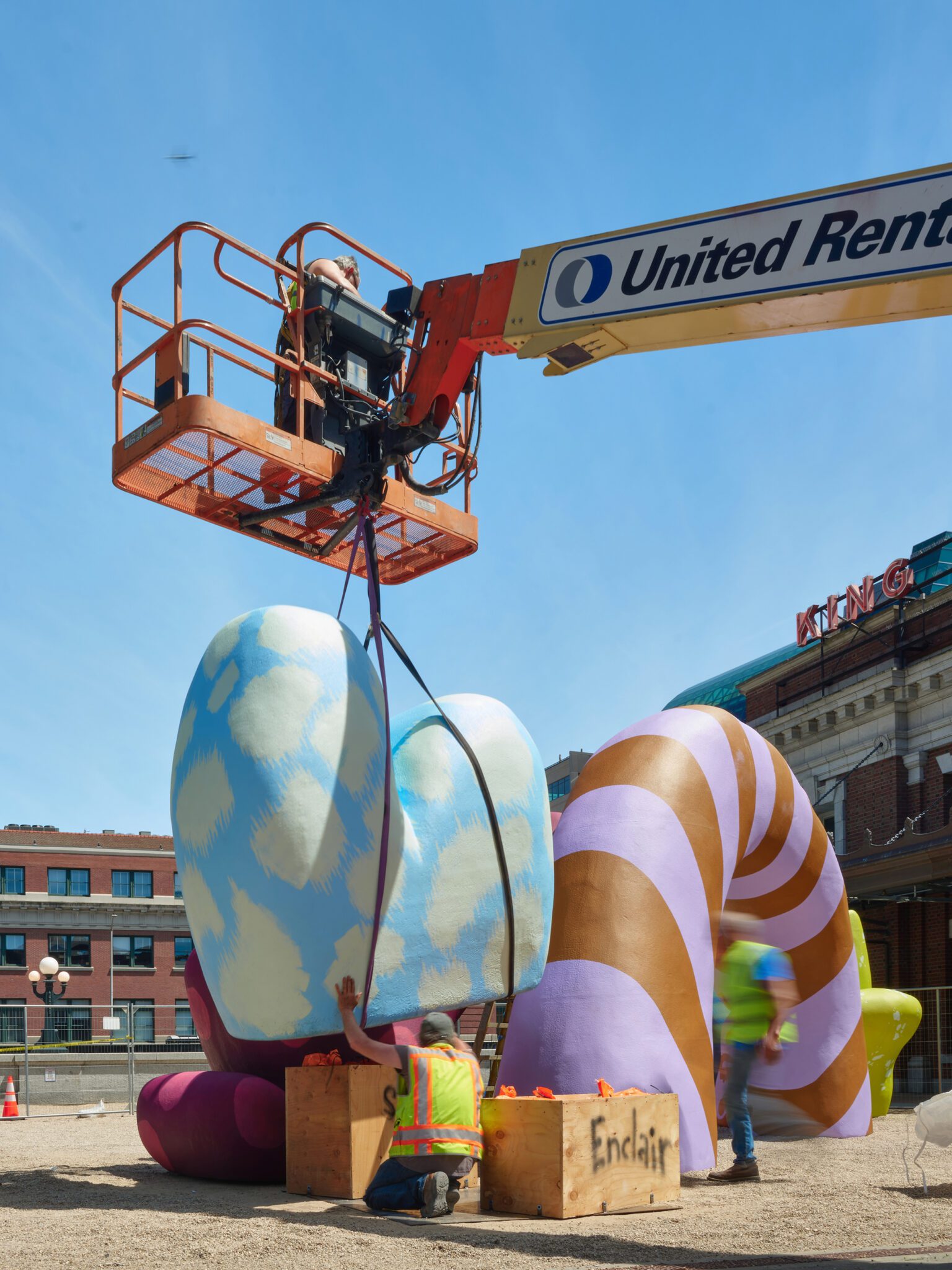 Installation by crane of the blue and yellow "sky" abstract shape on the plaza. The other shapes are in line with the one being installed.
