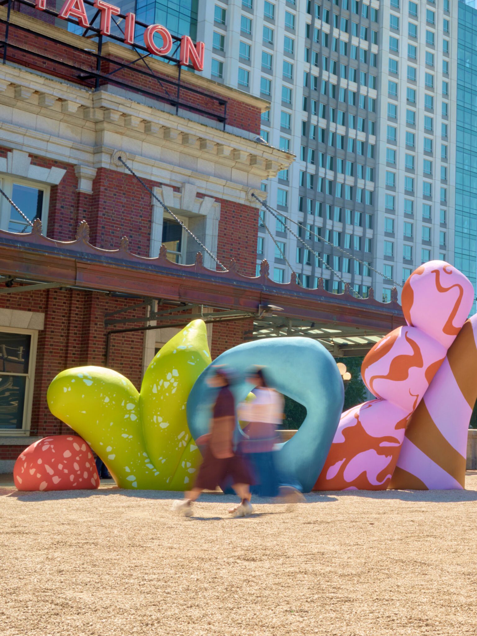Front view shot of Clouds of Belonging. The image has two people walking past that are blurry.