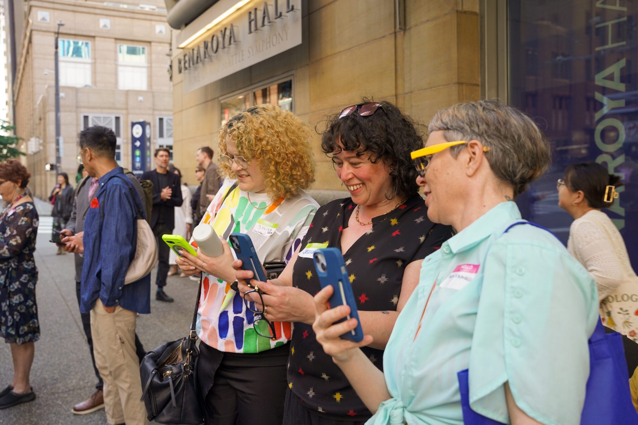 A group of three people centered in a crowd, holding their phones to access the AR visualization.