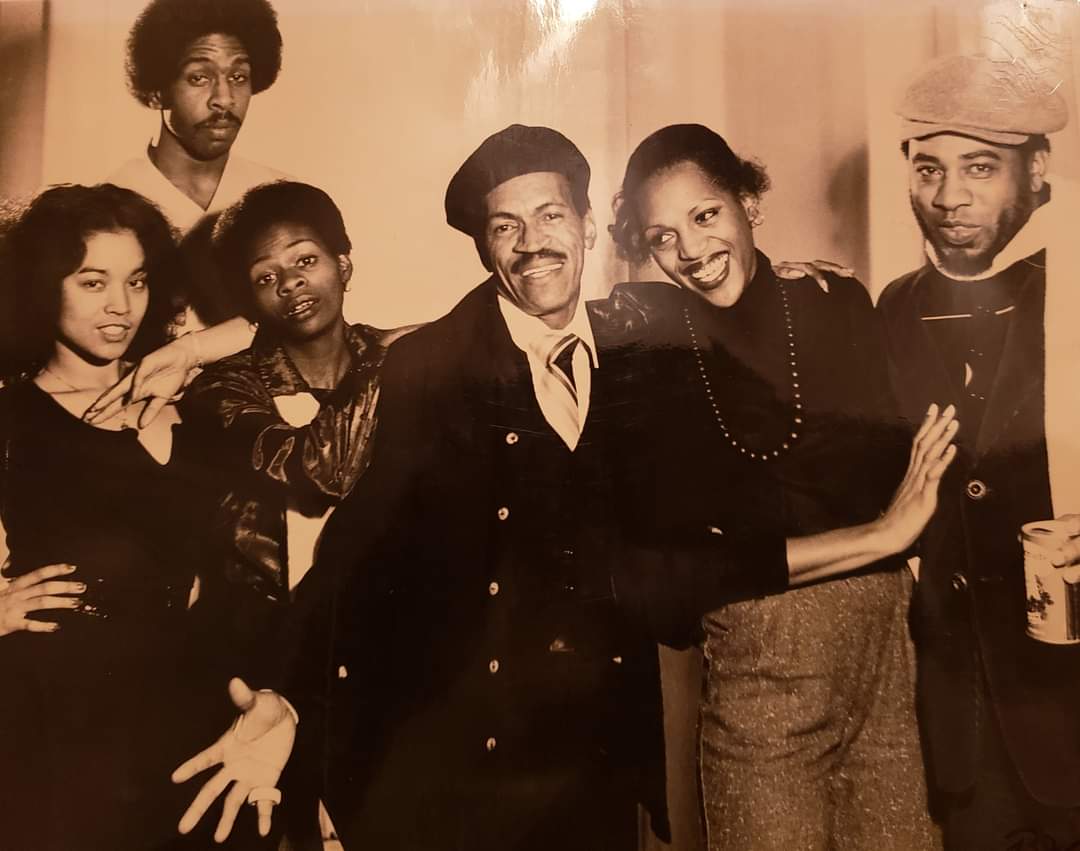 Sepia colored old photo of six Black men and women smiling and posing together