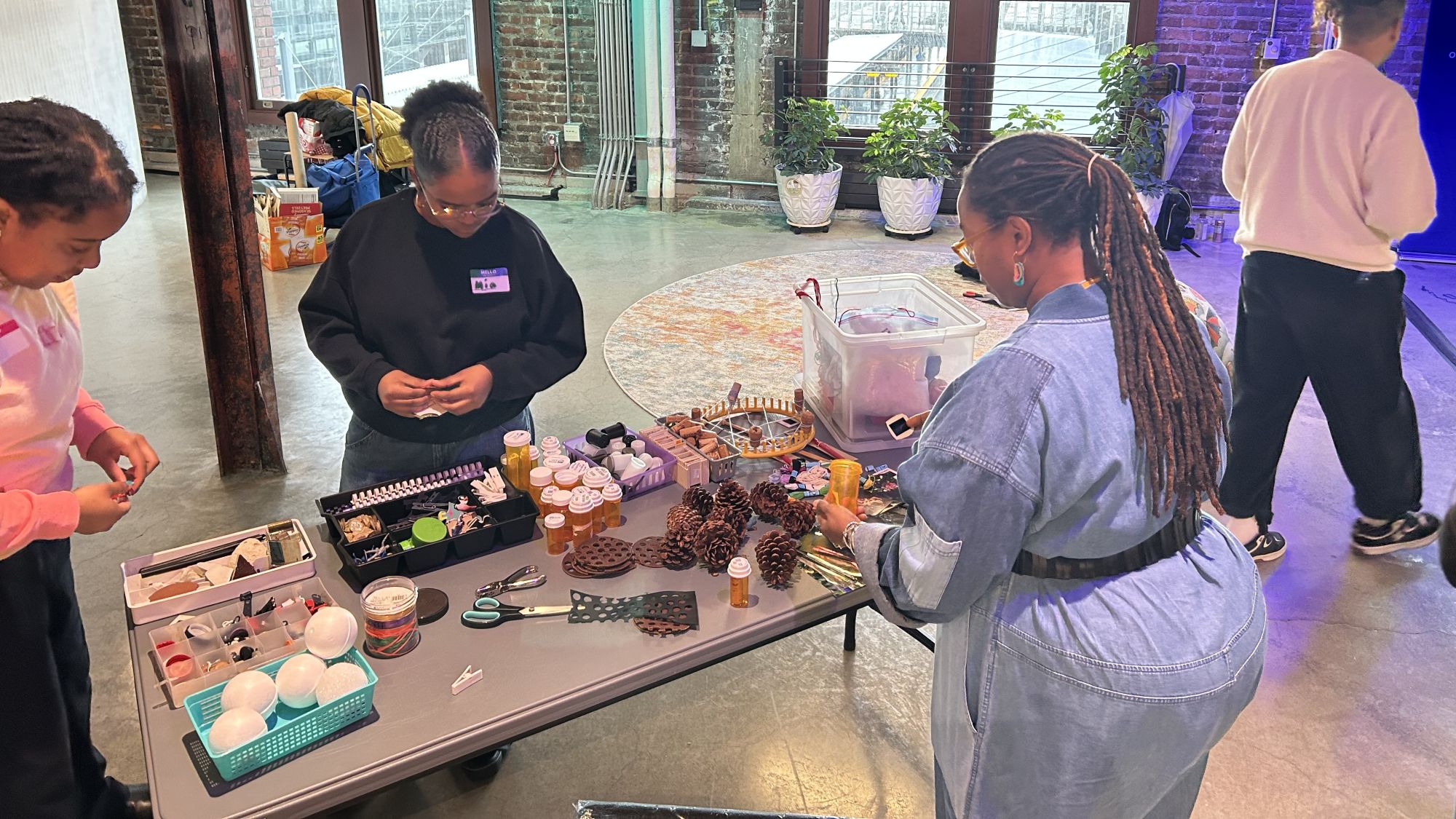 Three Black women gather around a table of crafting supplies